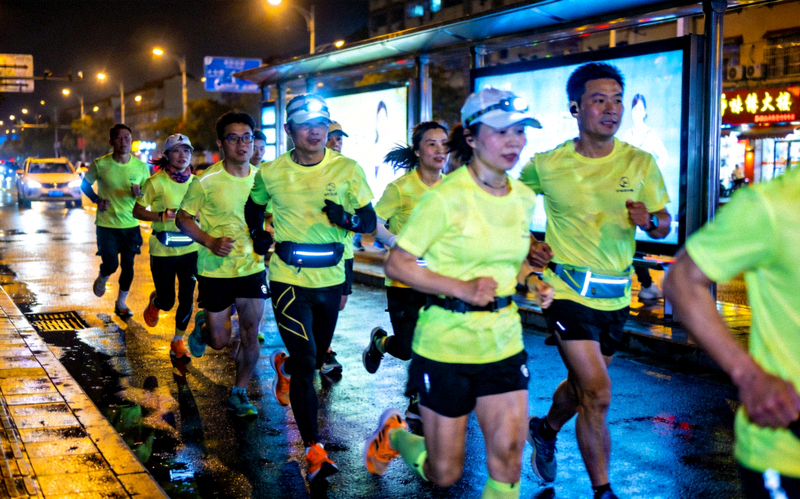城市夜跑团队在夜晚街道跑步的场景