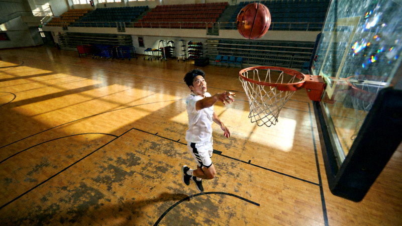 篮球运动员在室内球场进行三分球投篮训练的真实场景